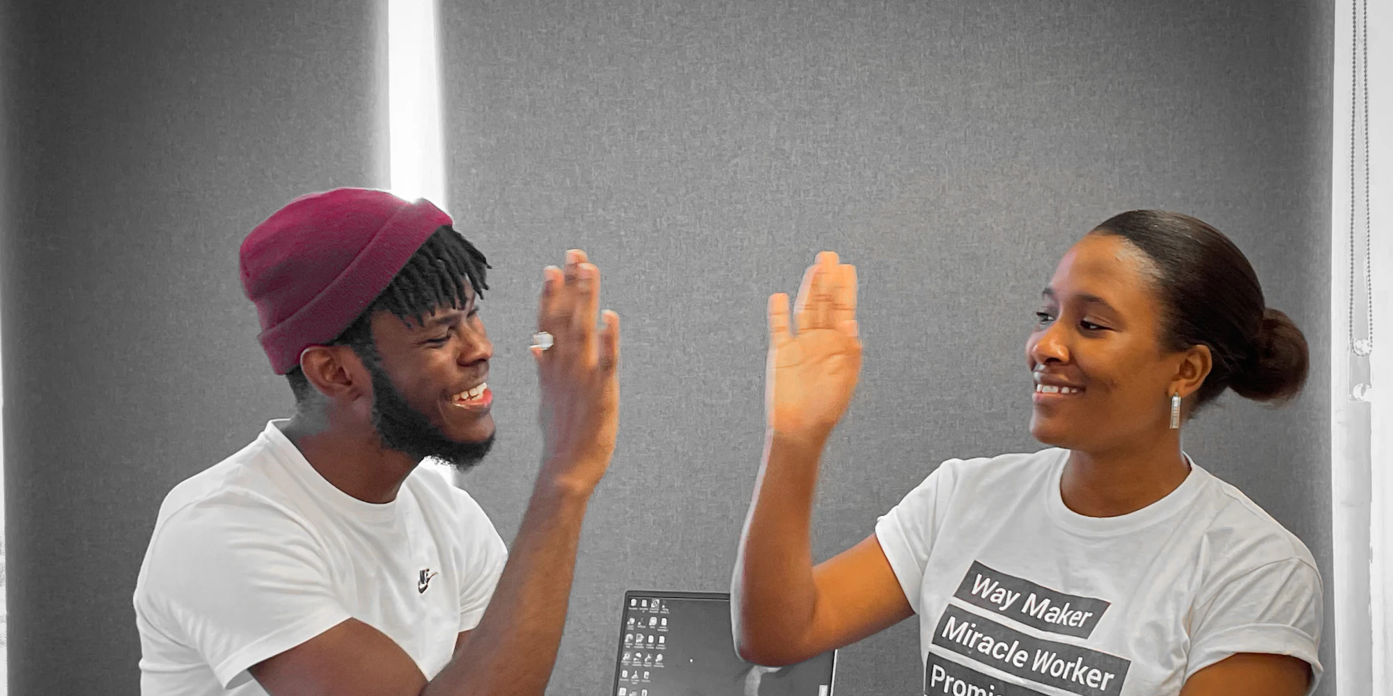 A man and a woman sitting at a table, smiling and high-fiving each other